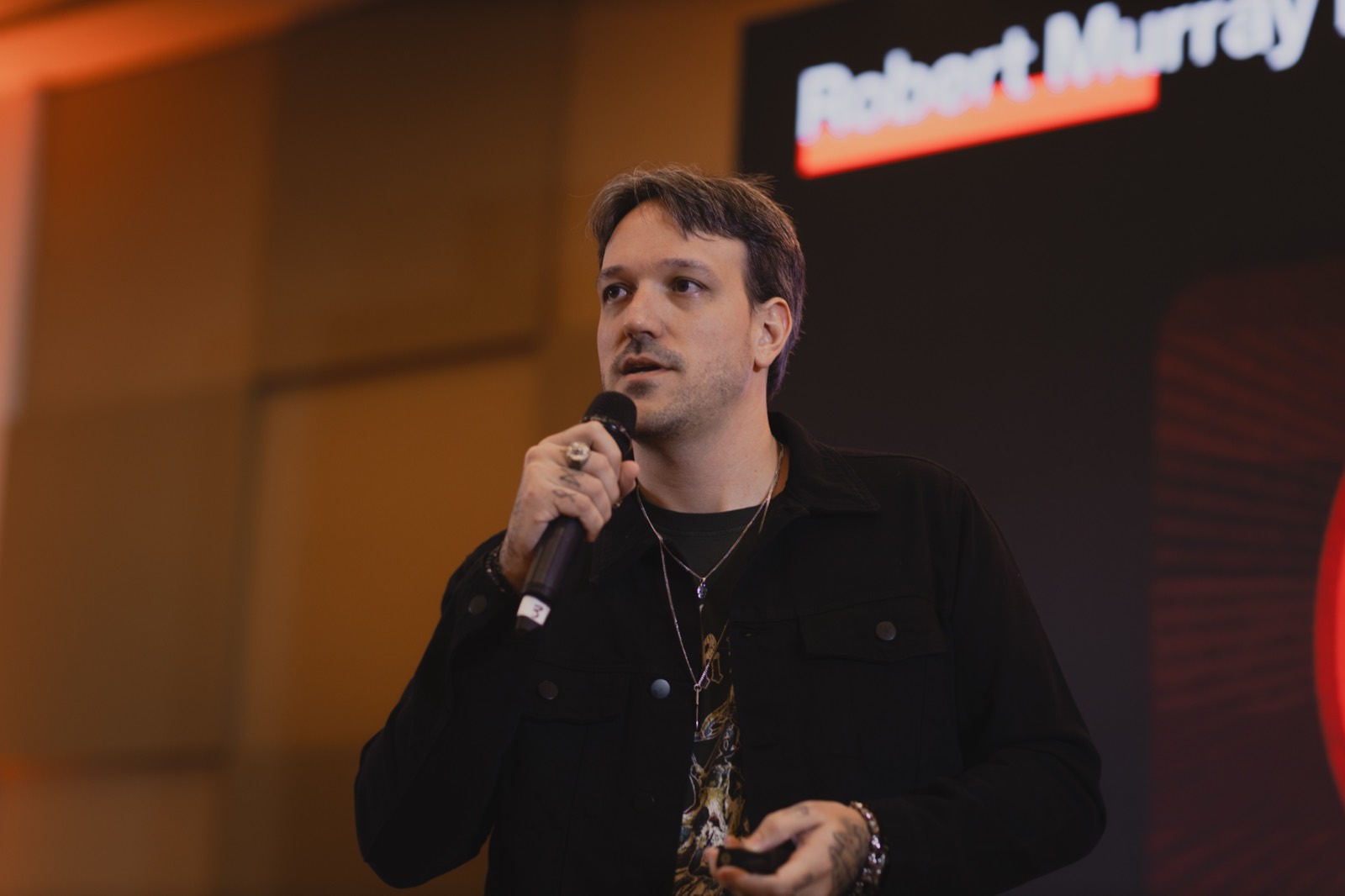 Marcelo Pinazza no palco, com microfone na mão, durante apresentação